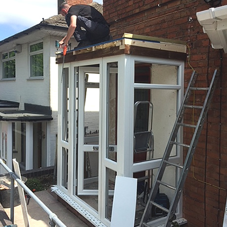 A newbuild entrance porch under construction with white profile and flat roof installed in Solihull by Solihull WDC
